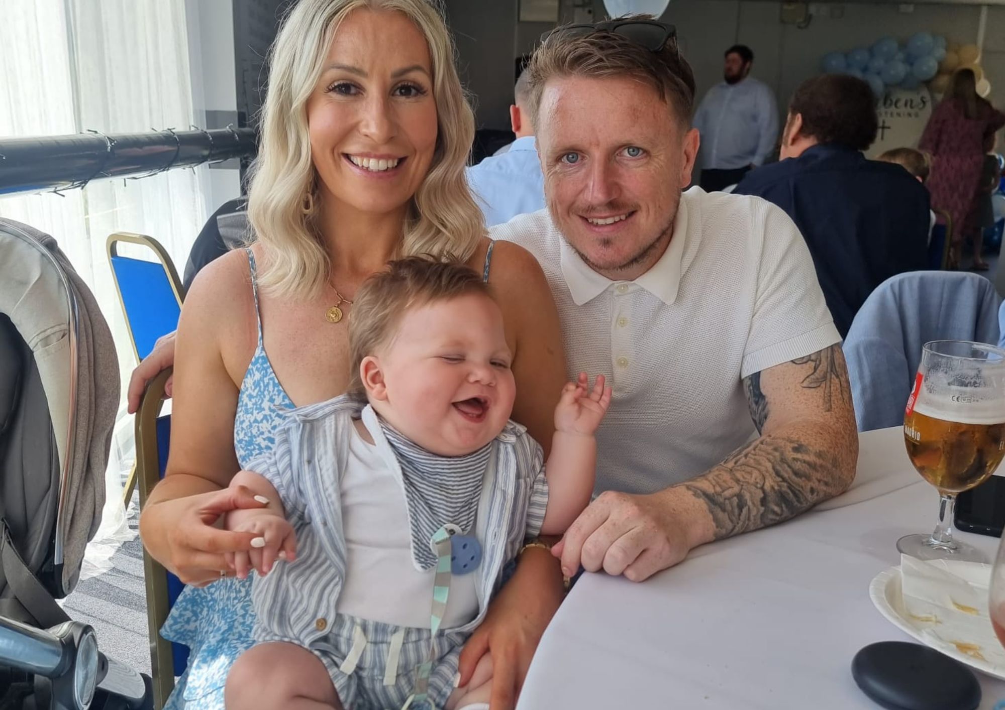 a family photo where mum, dad and baby are all smiling at the camera