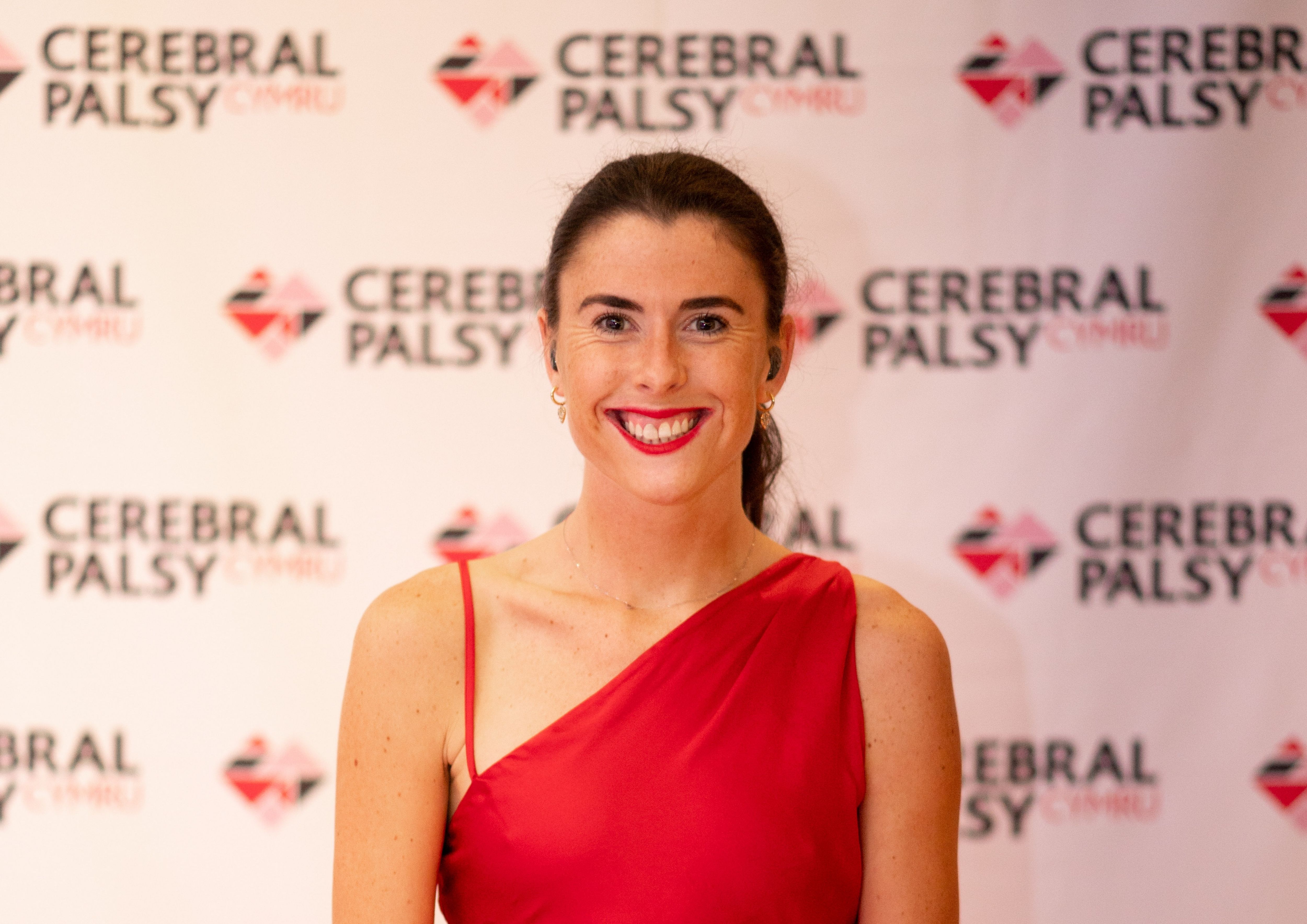 Oliva Breen smiles up at camera, in front of our branded step and repeat banner.