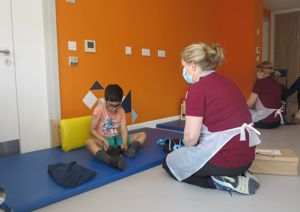 Young boy sits on the floor alongside one of our therapists.