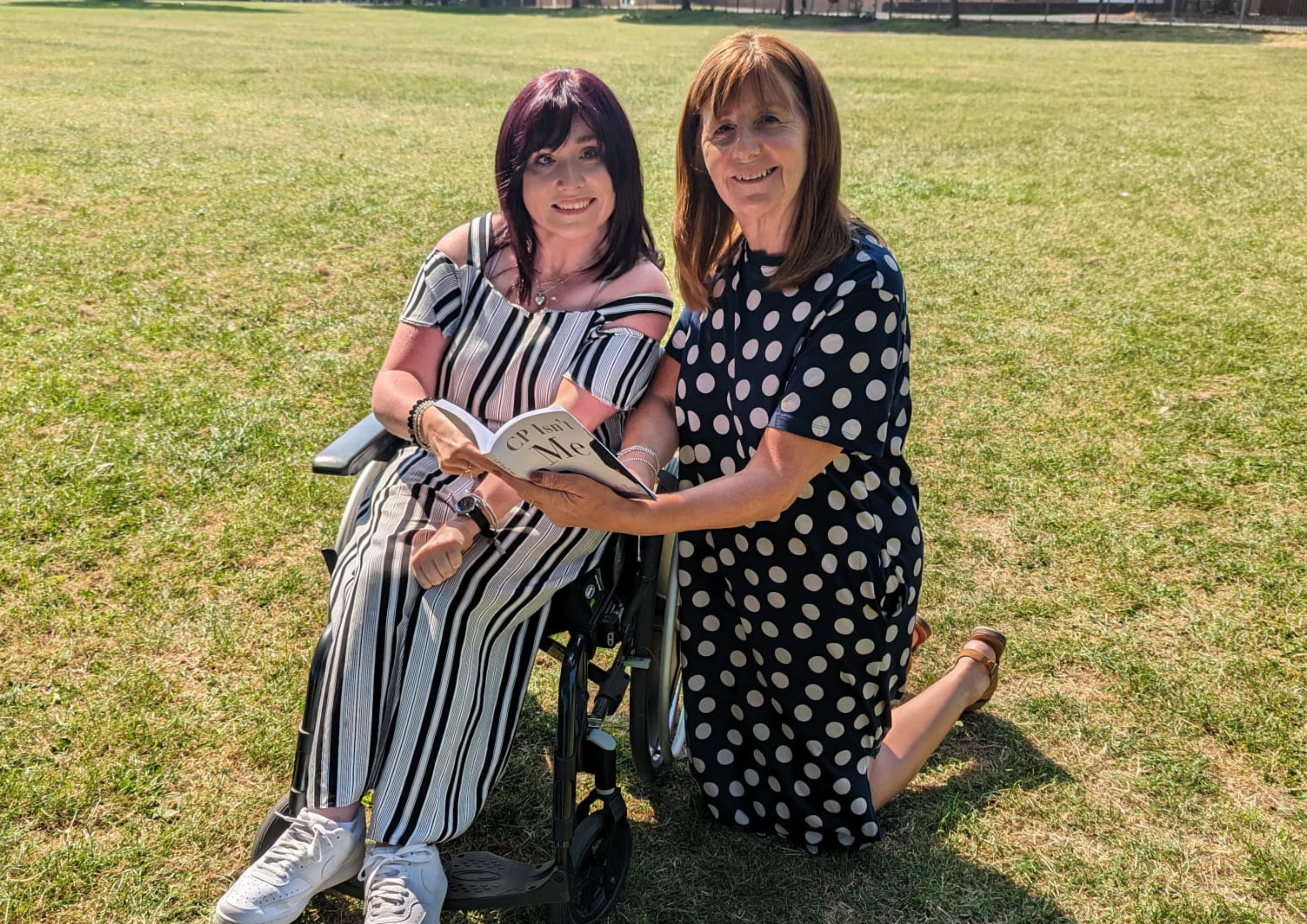 Samantha Maxwell pictured on the grass alongside Lesley Griffiths who is holding a copy of CP Isn't Me