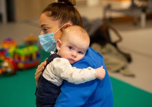 Baby being held by his mother, looking directly at the camera.