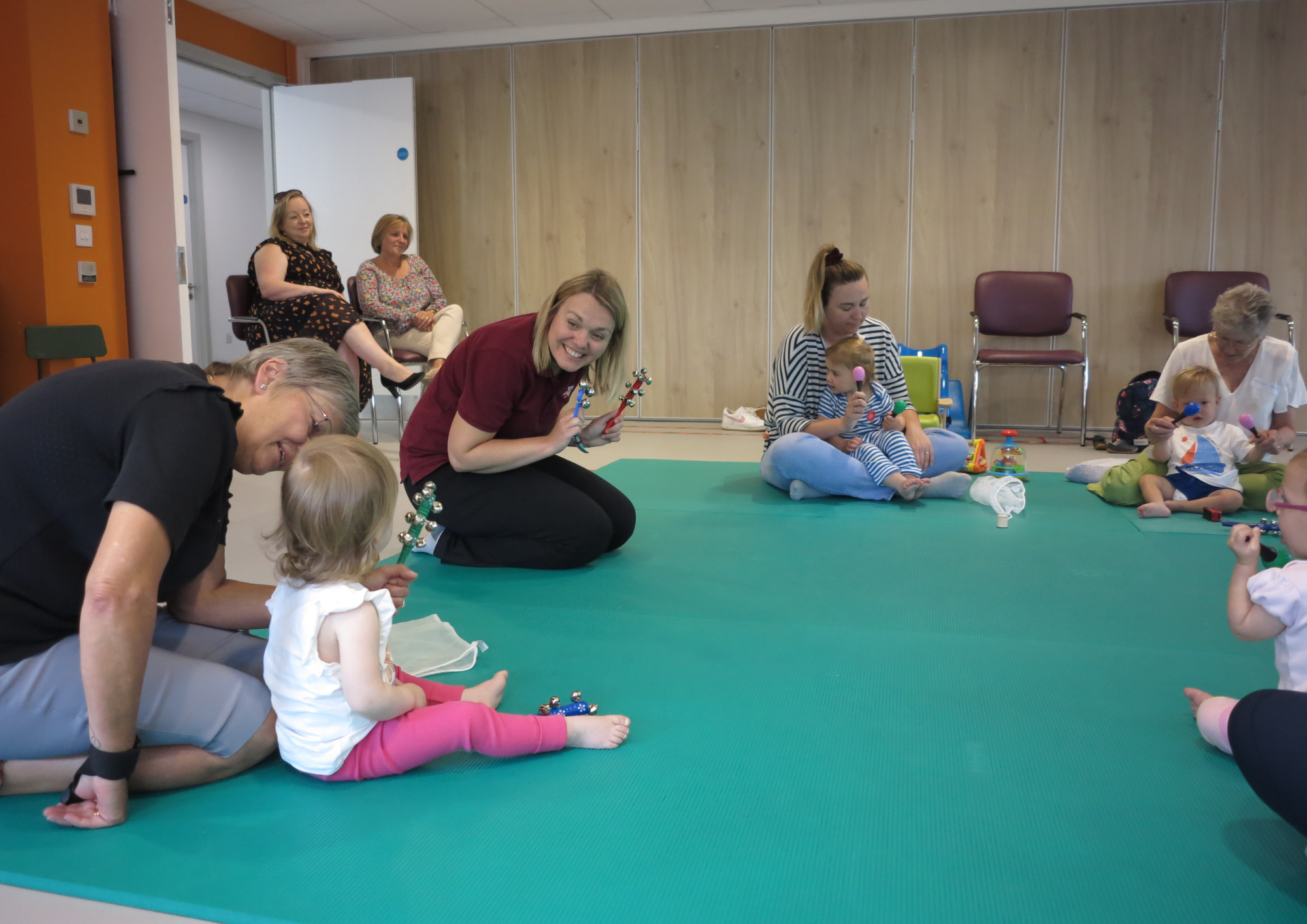 babies and their families sitting on the floor in a play group
