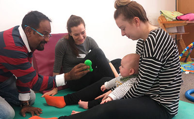 baby in mothers lap looking at toy