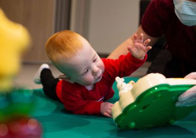 Photograph of baby boy reaching out towards a therapy toy.