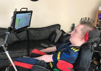 Photo of young adult in a wheelchair using eye gaze technology.