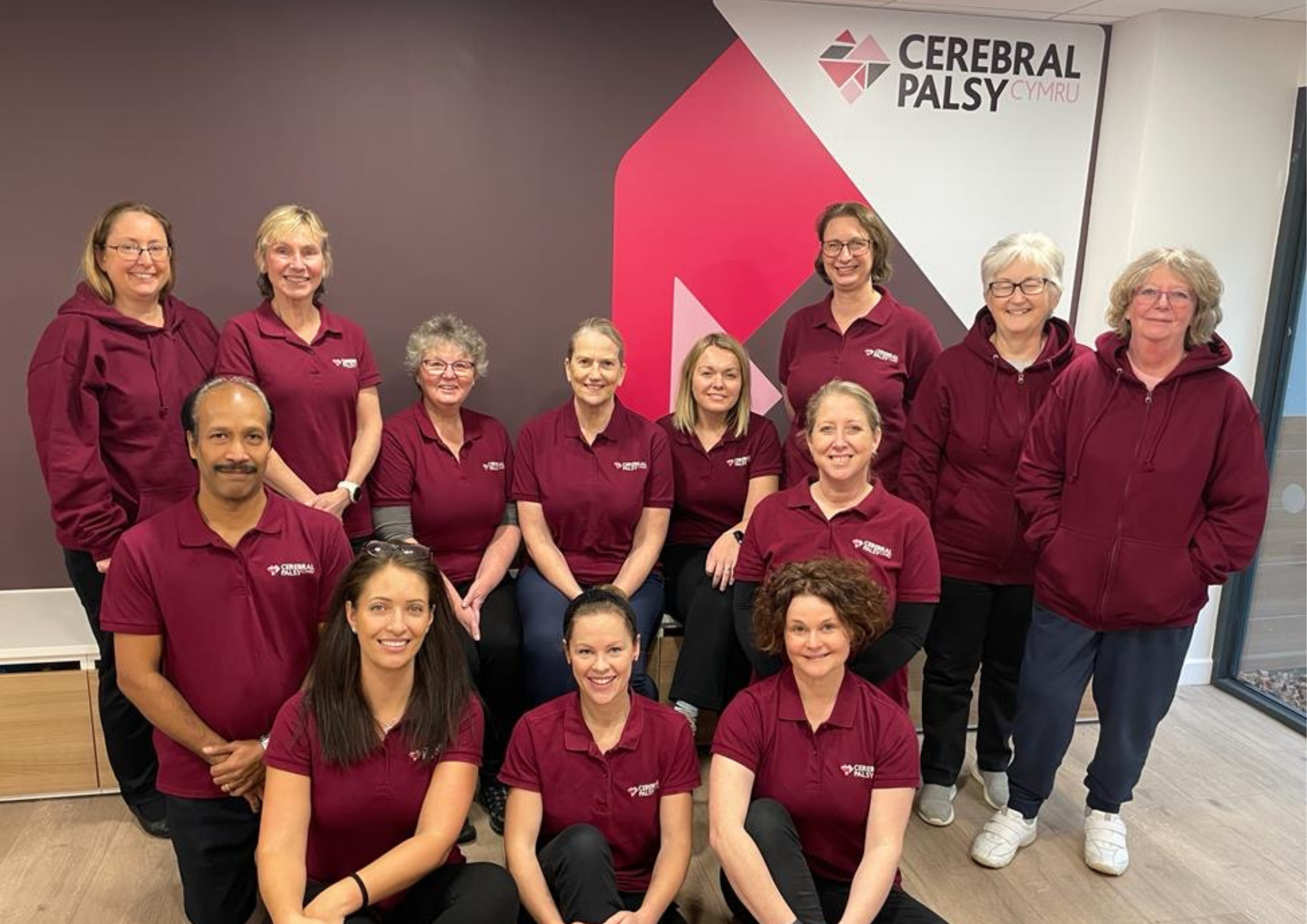 Photograph of our therapy team standing in front of our branded wall in our centre.