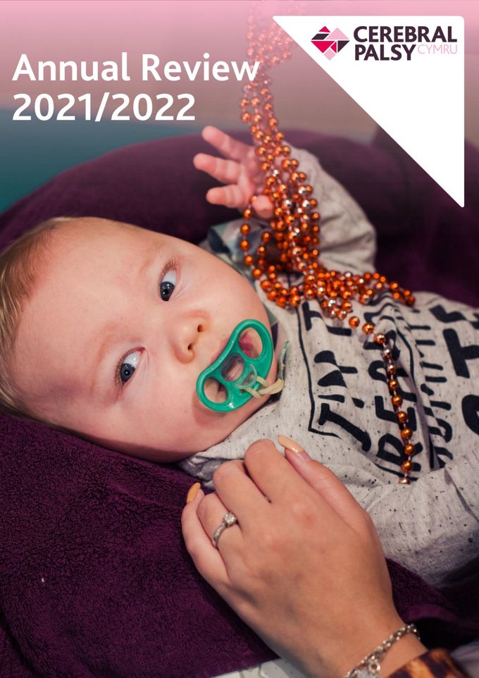 Screenshot of Annual Review 2021/2022. Photograph shows young boy with dummy, reaching up towards some beads.