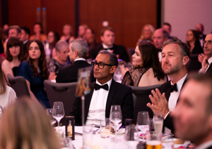 Photograph of group of people dressed in black tie, seated at our Better Start Ball. They are clapping in applause.