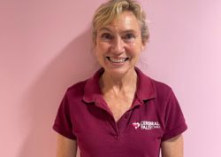 Photograph of our Clinical Expert Physiotherapist in front of pink wall.
