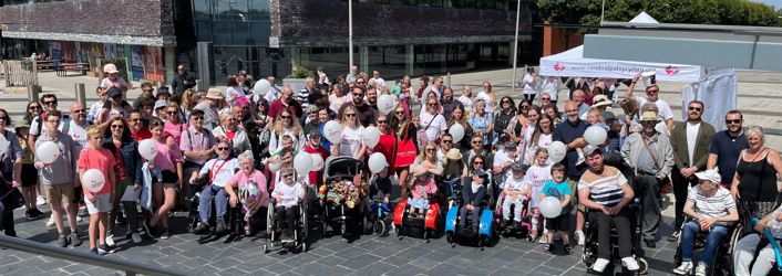 Photograph of large group of people holding Cerebral Palsy Cymru branded balloons. 