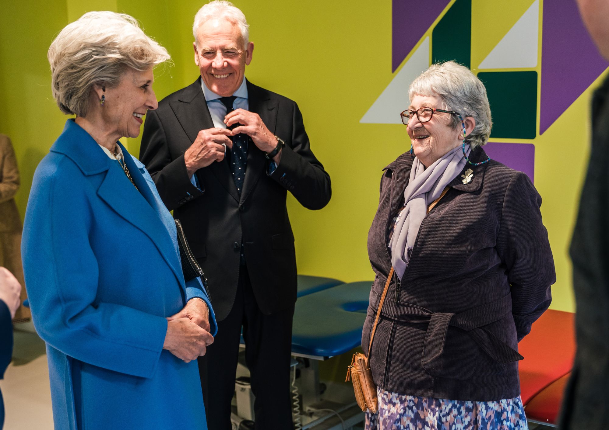 a lady in a blue coat smiling and laughing with a volunteer