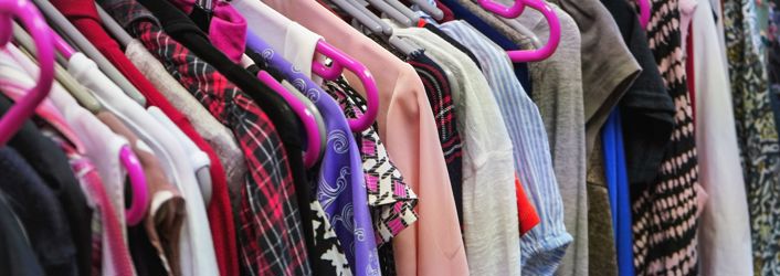 Photograph of a rail of clothing on hangers.