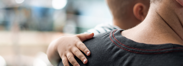 young boy placing hand on a mans shoulder.