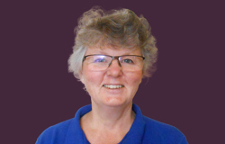 Senior therapist head shot with purple background.