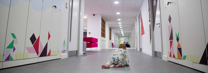 Photograph of a baby crawling across the floor of our new children's centre. 