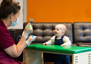 Photograph of baby girl looking up at therapist.