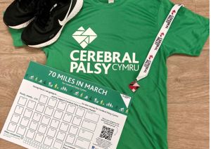 a photo of a green t-shirt, tracker chart and medal on the floor 