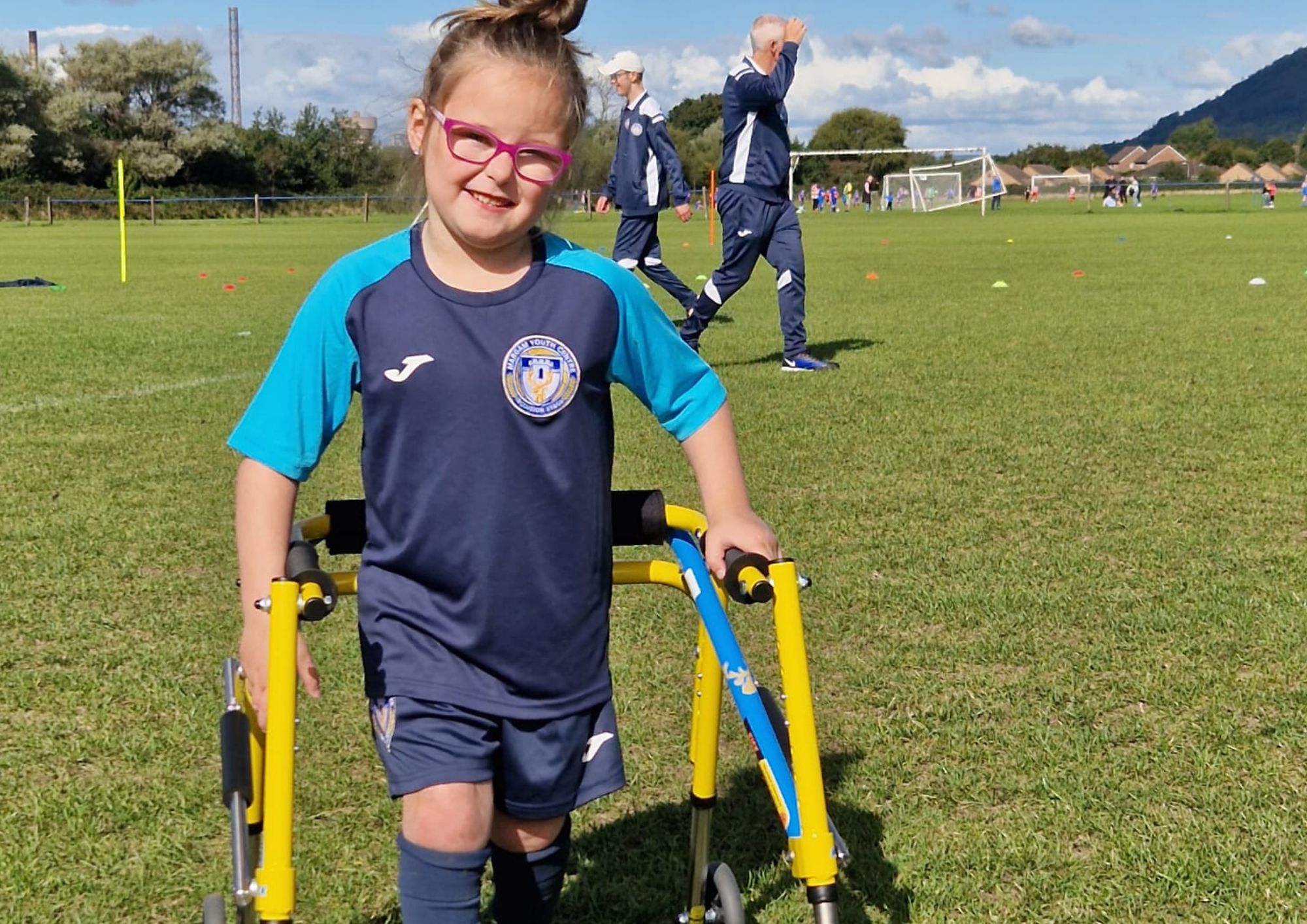 young girl using walking frame smiling at camera