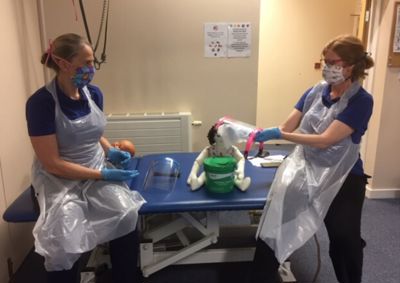 two therapists with visors, gloves and aprons