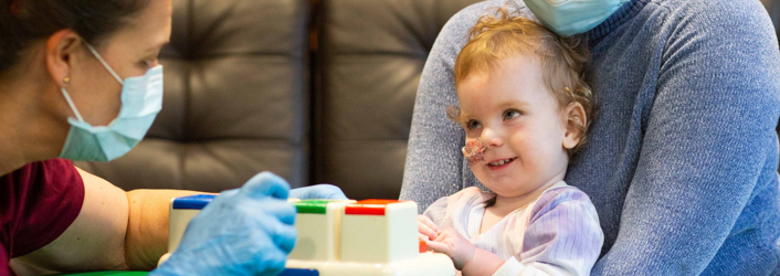 Photograph of baby girl looking up at therapist.