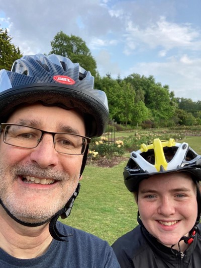 Man and woman smiling at camera wearing cycling helmets. 