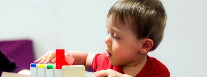 little boy in red t-shirt playing with pop up toy/