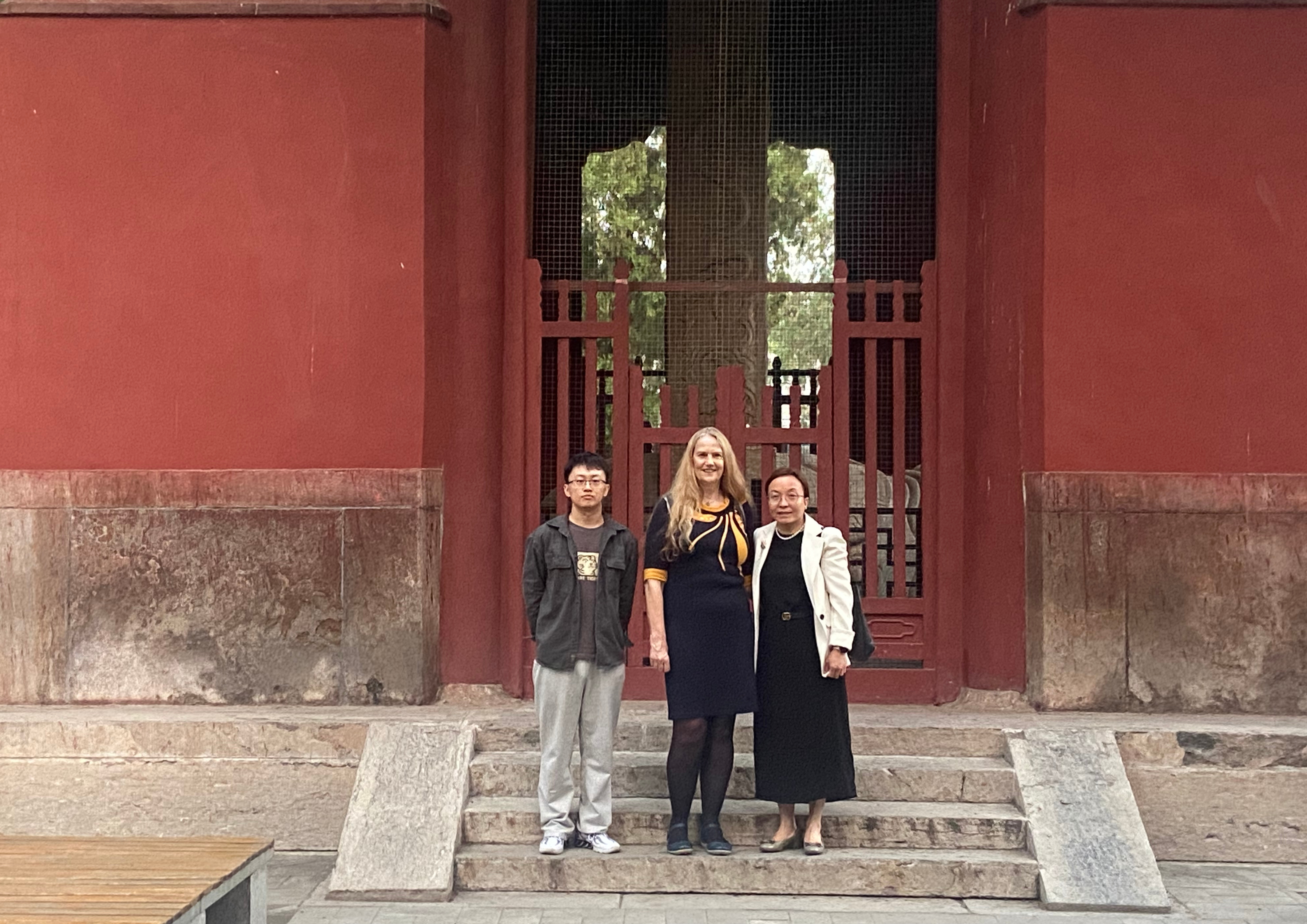 Jenny is pictured alongside a man and woman outside in front of a building in China