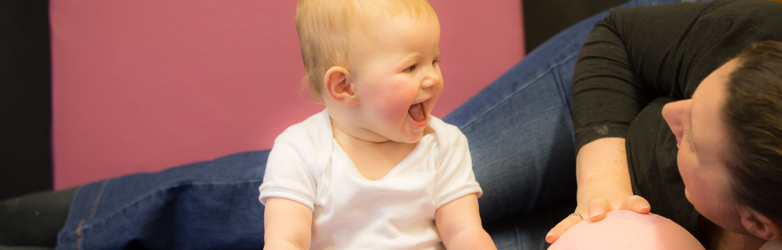 baby laughing at mum playing with a ball