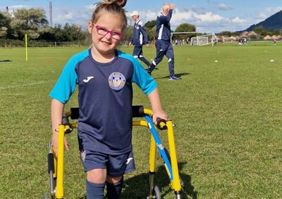 Photo of young girl in football kit, holding frame.