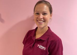 Photograph of one of our physiotherapists in front of a pink wall.