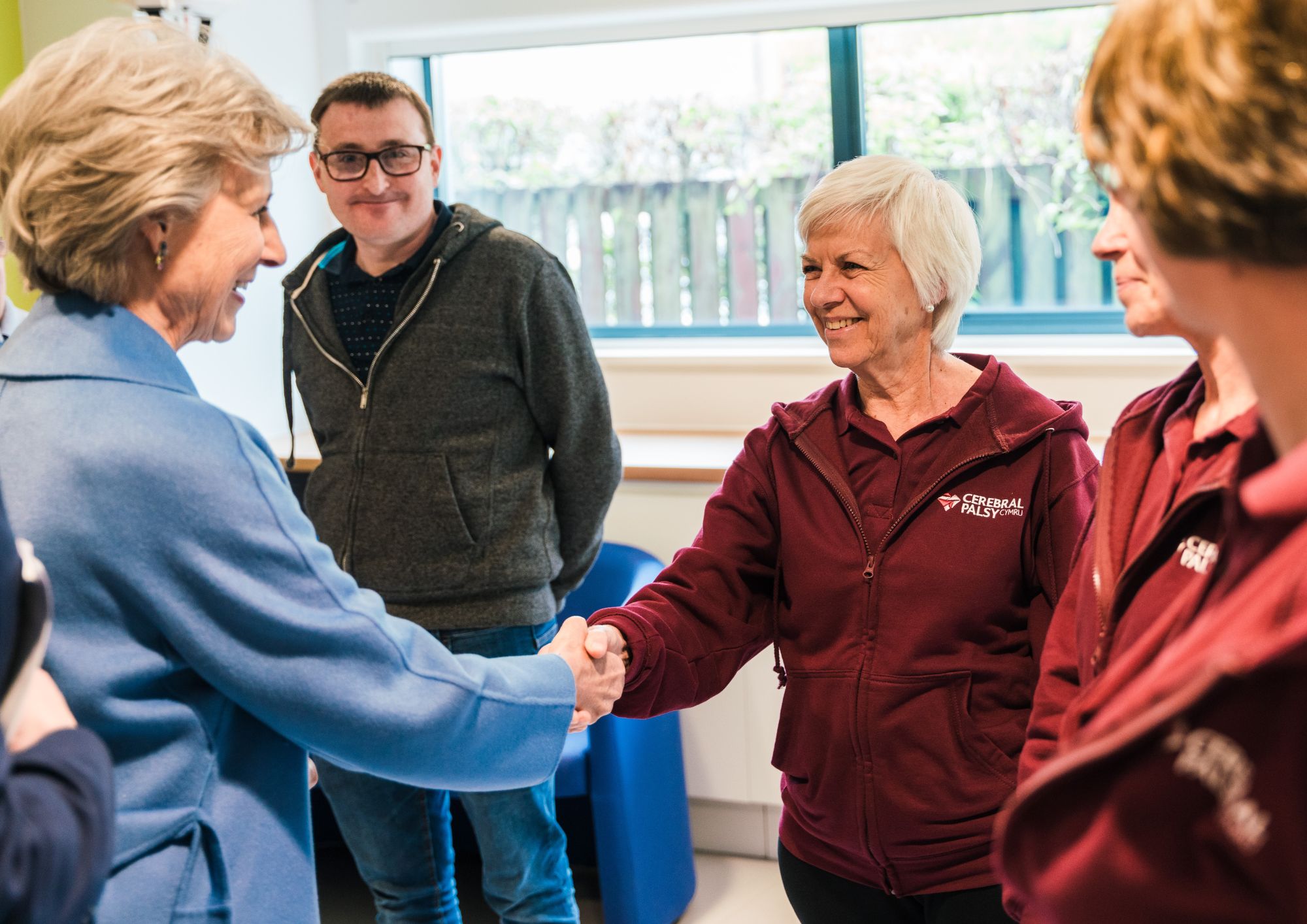 a lady in a blue coat shaking hands with a therapist