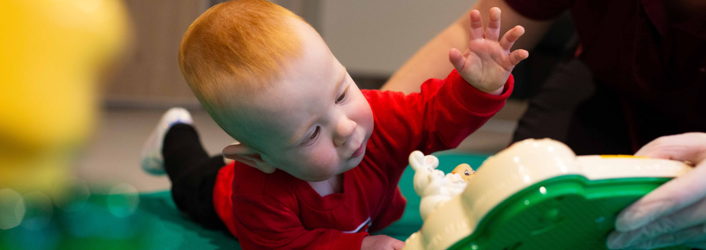 Photograph of baby boy playing with a therapy toy. 