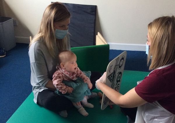 a therapist sat on the floor with a mum and her baby