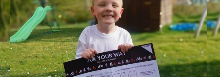 Photograph of young boy holding 70K YOUR WAY tracker. 