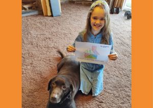 Little girl with dog holding coloured in tangram house