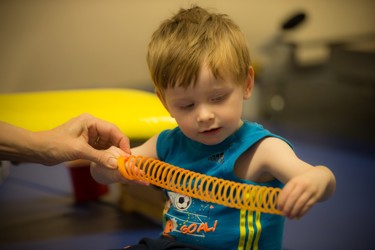 Photograph of young boy holding a spring toy.