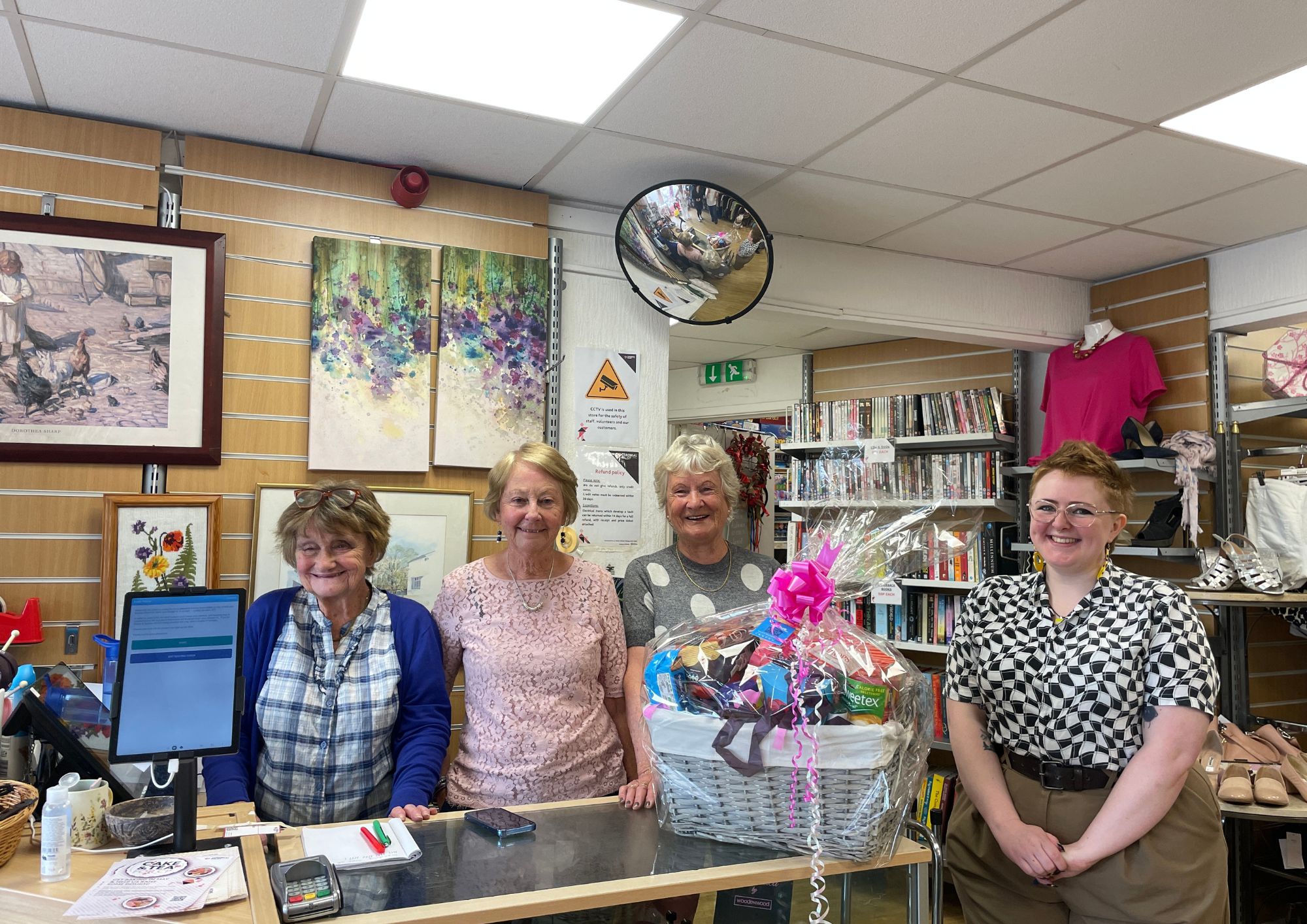 Volunteers and our Volunteer Coordinator smile at camera with hamper
