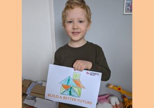 Little boy holding coloured in tangram house